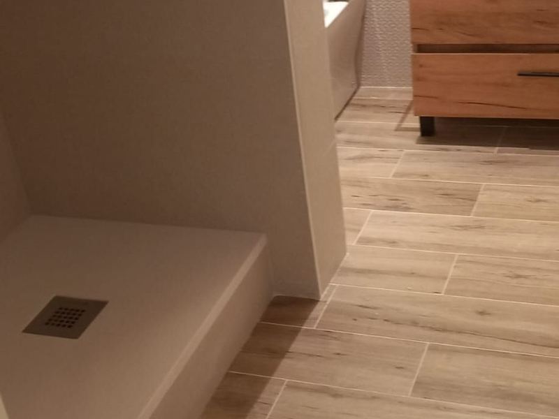 Baño reformado con plato de ducha de obra con hornacina, mueble de madera y suelo porcelánico