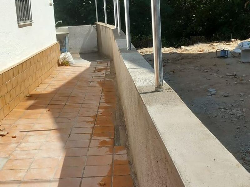 Muro de bloques enfoscado con postes galvanizados recibidos en la coronación para montar la valla